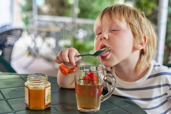 Bambino Sta Bevendo Con Miele Sulla Veranda Estiva Ragazzino Lecca — Foto Stock