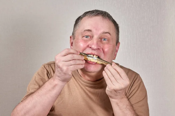 Homem comendo peixe cheiroso frito segurando peixe com as mãos na frente da cara — Fotografia de Stock