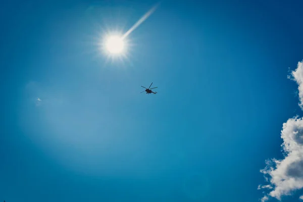 Egy helikopter sziluettje a kék égbolton felhőkkel. — Stock Fotó