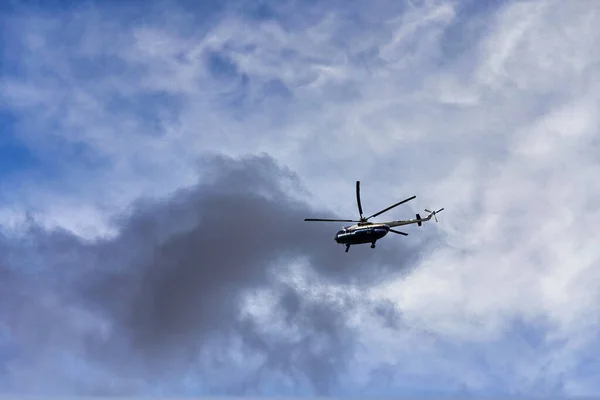 Hubschrauber fliegen vor dem Hintergrund von Wolken und blauem Himmel — Stockfoto