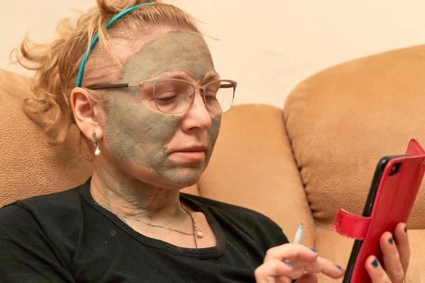 Abuela con una máscara cosmética en su cara hecha de arcilla curativa Fotos De Stock Sin Royalties Gratis