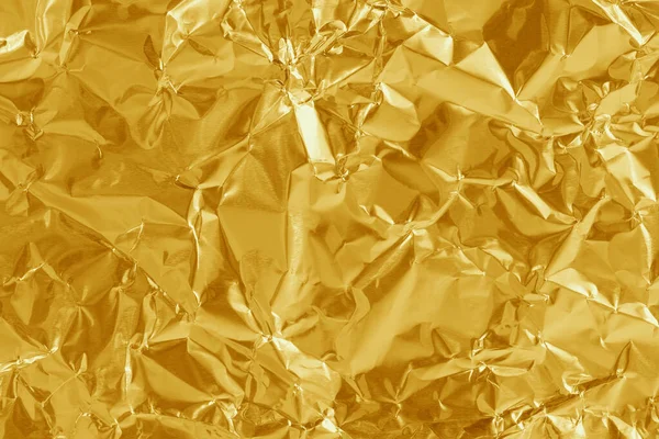 Gold foil leaf shiny texture, abstract yellow wrapping paper for background and design art work.