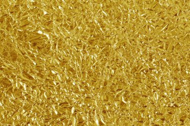 Altın folyo yaprağının parlak dokusu, arkaplan ve tasarım çalışmaları için soyut sarı ambalaj kağıdı.