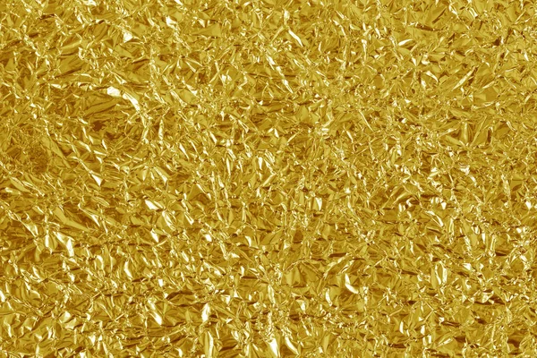 Altın folyo yaprağının parlak dokusu, arkaplan ve tasarım çalışmaları için soyut sarı ambalaj kağıdı.