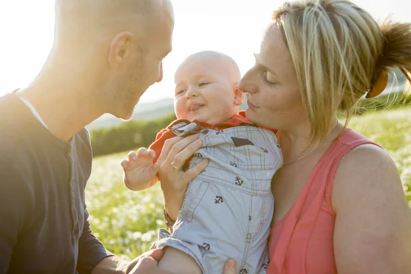 Happy family of three. Father, mother and baby playing outside in summer at sunset time. — Stock Photo, Image