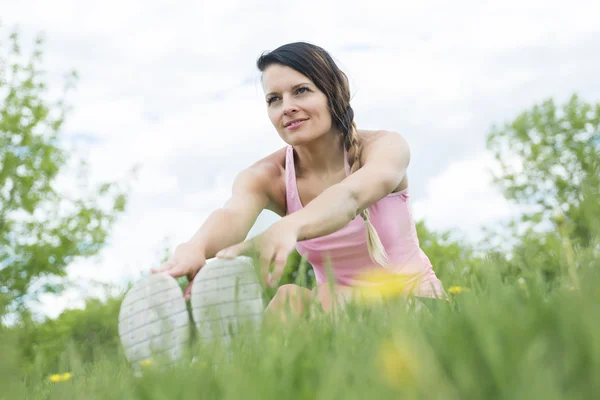 Jovem atleta feminina excercando e se alongando em um parque — Fotografia de Stock