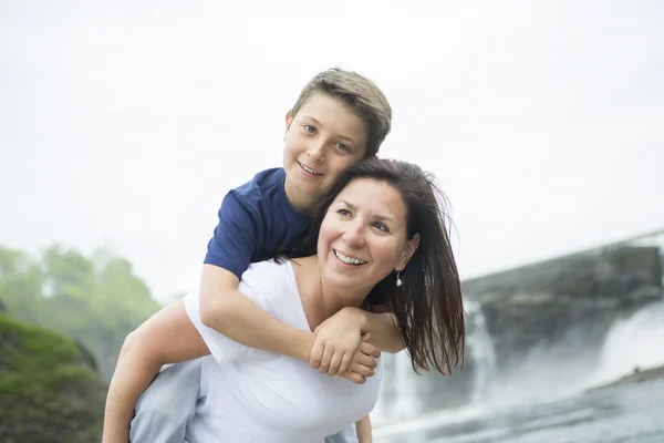 Moeder en zoon spelen voor een waterval — Stockfoto