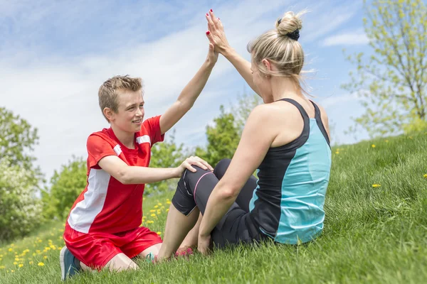 Счастливые сын и мать делают упражнения в летнем парке — стоковое фото