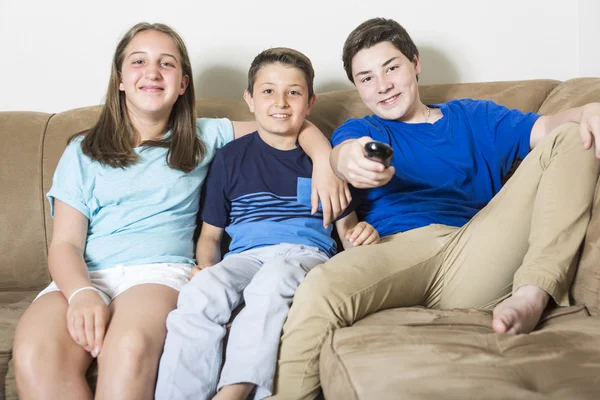 Οικογένεια κάθεται στον καναπέ βλέποντας τηλεόραση μαζί — Φωτογραφία Αρχείου