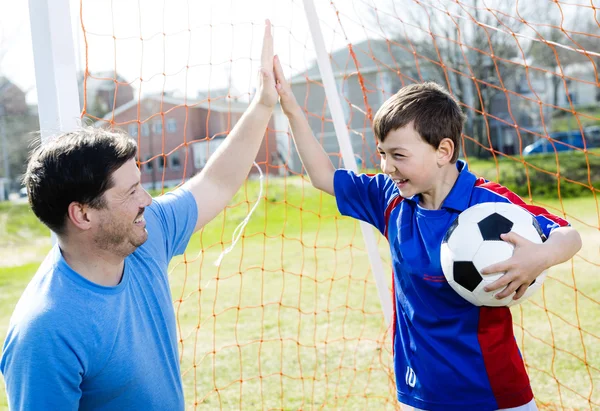 Hombre con niño jugando al fútbol en el campo —  Fotos de Stock