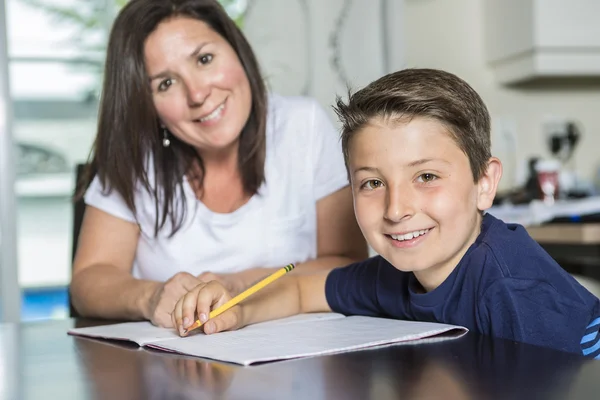 Moeder zoon met huiswerk aan tafel helpen — Stockfoto