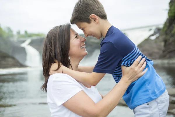 Mother and son playing in front of a waterfall — Stock Photo, Image