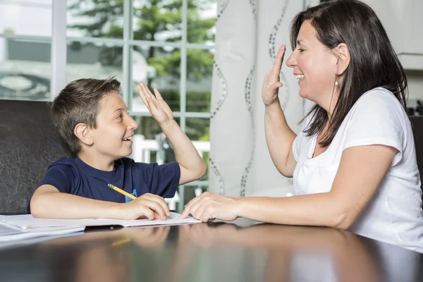 Мати допомагає сину з домашньою роботою за столом — стокове фото
