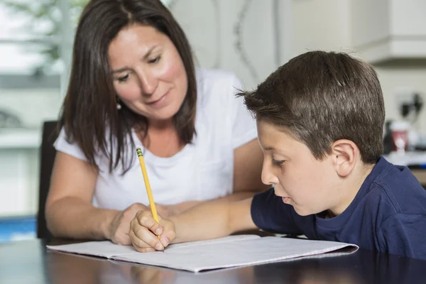 Mère aidant fils avec les devoirs à la table — Photo