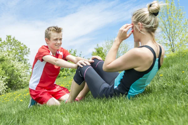 Happy son and mother are doing exercises in the summer park — Stock Photo, Image