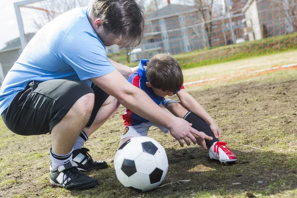 Mann mit Kind spielt Fußball auf Spielfeld — Stockfoto