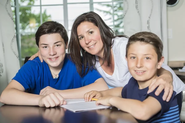 Moeder zoon met huiswerk aan tafel helpen — Stockfoto