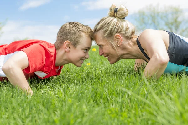 Glad son och mor gör övningar i parken sommaren — Stockfoto