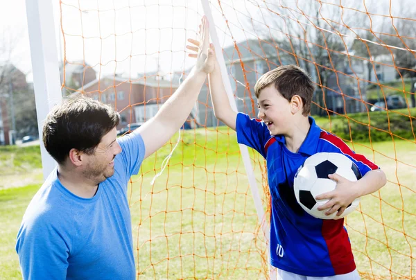 Uomo con bambino che gioca a calcio in campo — Foto Stock