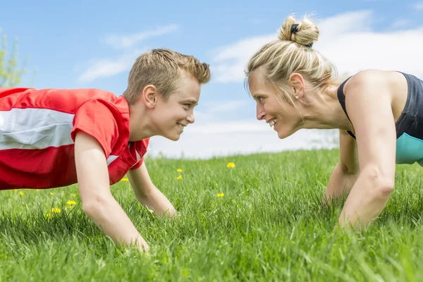 Feliz filho e mãe estão fazendo exercícios no parque de verão — Fotografia de Stock