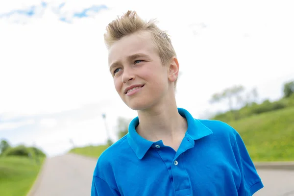 Jonge gelukkig lachend mannelijke tiener blond jongenskind buiten in de zomer zon, een blauwe trui te dragen — Stockfoto