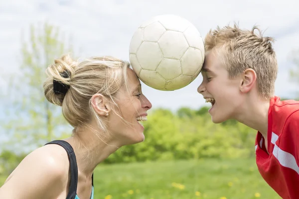 Jovem família feliz jogando futebol ao ar livre em um dia de verão — Fotografia de Stock