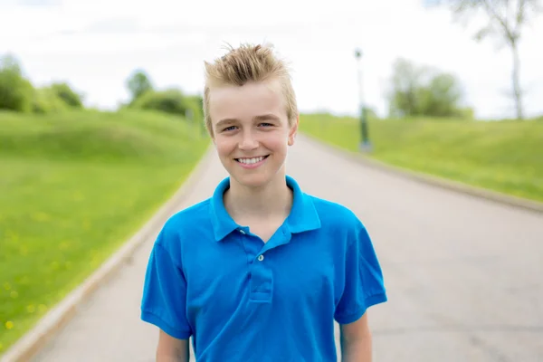 Jovem feliz sorrindo menino masculino adolescente loiro criança fora no verão sol vestindo uma camisola azul — Fotografia de Stock