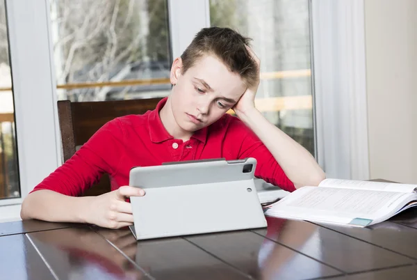 Хлопчик-підліток вчиться важко над своєю книгою вдома — стокове фото