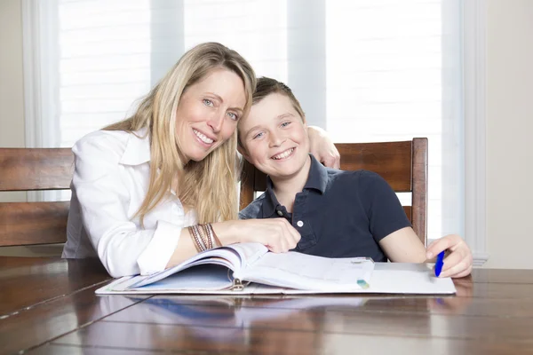 Madre ad una casa tavola aiutando il suo piccolo figlio con i suoi compiti — Foto Stock