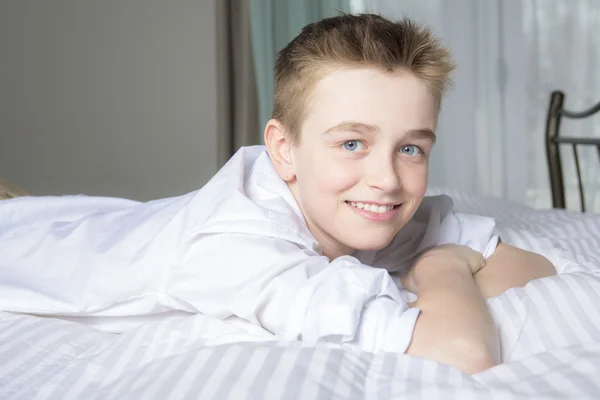 Feliz niño sonriente acostado en la cama en casa — Foto de Stock