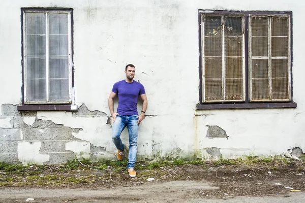 Привлекательный молодой человек стоит на стене улицы — стоковое фото