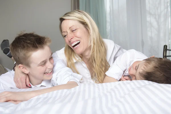 Madre y dos hijos relajándose juntos en la cama — Foto de Stock