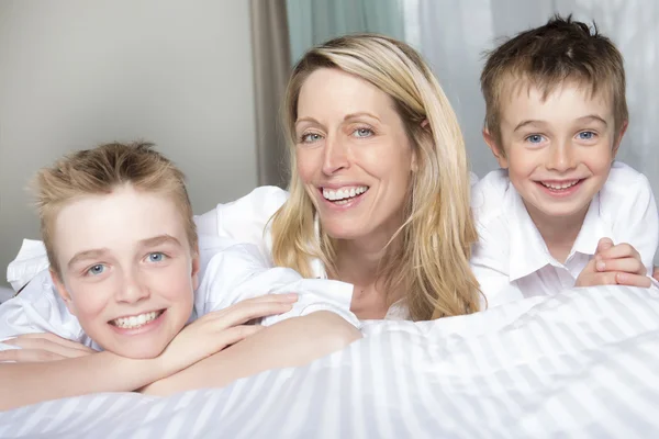 Madre y dos hijos relajándose juntos en la cama — Foto de Stock
