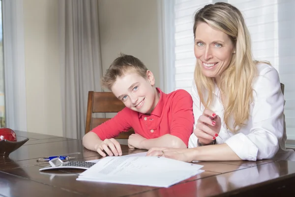 家彼女の小さな息子の宿題を手伝ってテーブルで母 — ストック写真