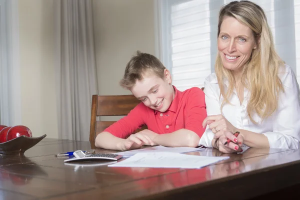 Madre ad una casa tavola aiutando il suo piccolo figlio con i suoi compiti — Foto Stock