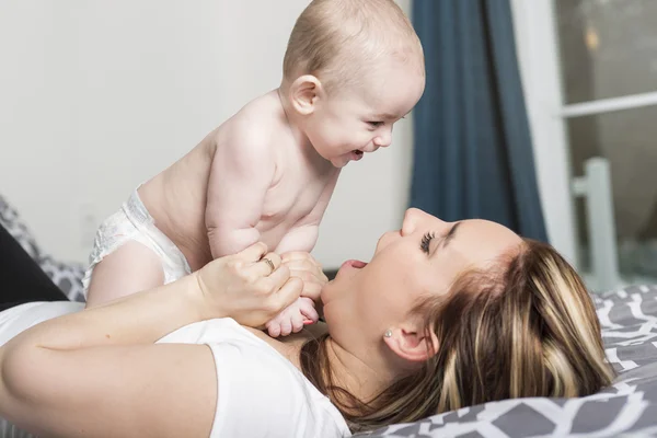 Portrett av lykkelig ung mor med baby i sengen hjemme – stockfoto