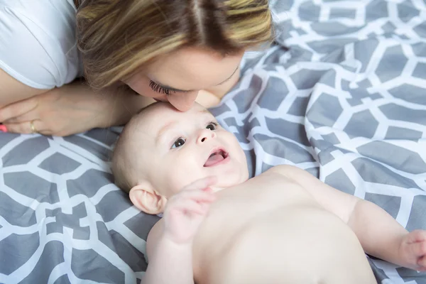 Ritratto di giovane madre felice con un bambino nel letto di casa — Foto Stock