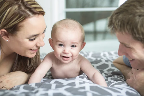 Família feliz de pai, mãe e bebê brincando na cama — Fotografia de Stock