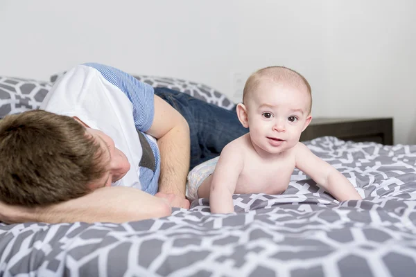 Retrato de jovem pai feliz com um bebê na cama em casa — Fotografia de Stock