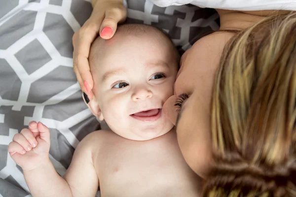 Boldog fiatal anya a baba az ágyban otthon portréja — Stock Fotó