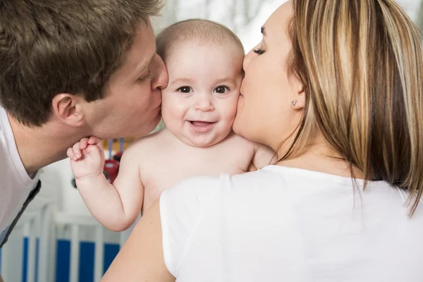 Primo piano ritratto di giovani genitori baciare bellissimo figlio appena nato — Foto Stock