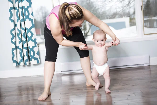 Mère tenant un bébé sous ses bras dans le salon — Photo