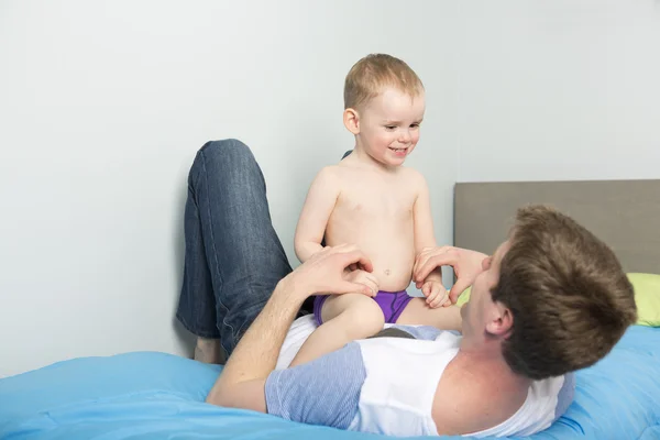 Pai jogar com seu filho menino na cama em casa — Fotografia de Stock