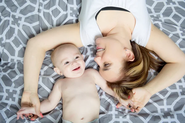 Portrait of happy young mother with a baby in the bed at home — Stock Photo, Image