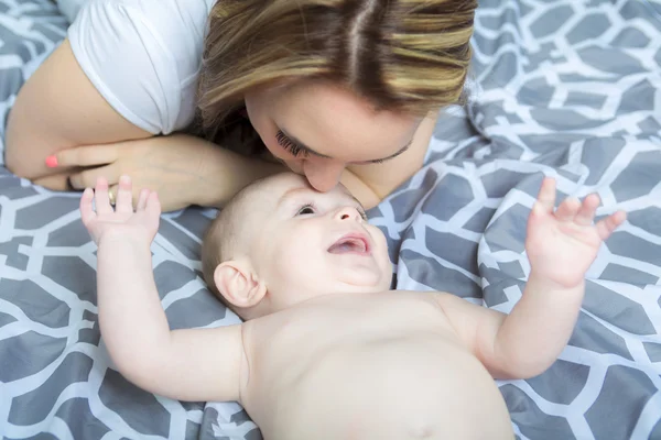 Portrait of happy young mother with a baby in the bed at home — Stock Photo, Image