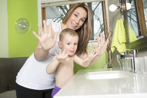 Bonne mère et enfant se lavent les mains avec du savon dans la salle de bain — Photo