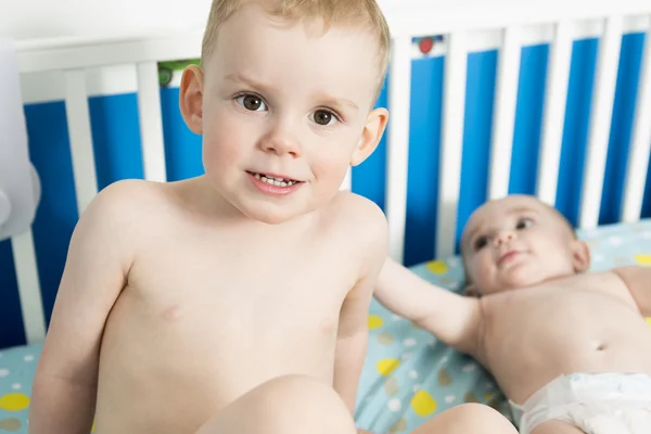 Bébé mignon dans la crèche avec son frère — Photo