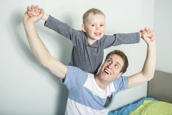 Pai jogar com seu filho menino na cama em casa — Fotografia de Stock