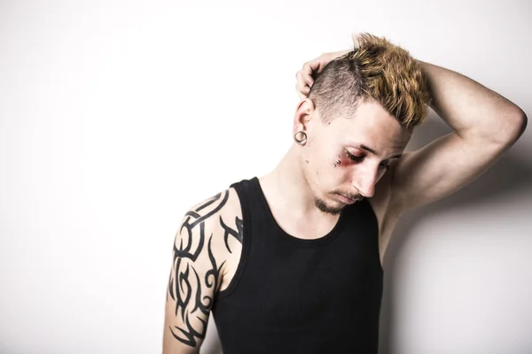 Красивый стильный молодой человек с татуировкой и пирсингом — стоковое фото
