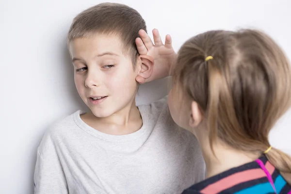 Junges Mädchen, das Jungen ein Geheimnis erzählt — Stockfoto